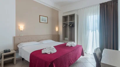 Camera da letto semplice con letto matrimoniale e porta finestra con tende