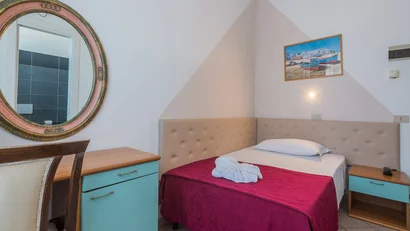 Camera singola con letto, specchio ovale e comodini azzurri