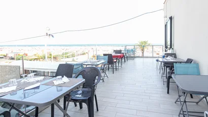 Terrazza con tavoli apparecchiati e vista sul mare