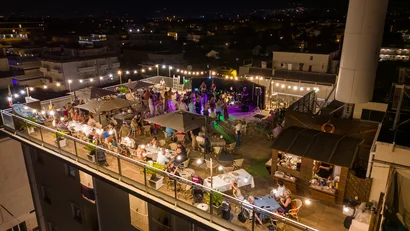 Festa serale su una terrazza panoramica con musica dal vivo e ospiti seduti e in piedi
