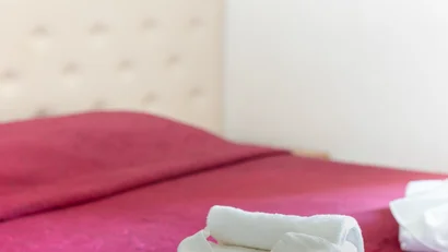 Asciugamani piegati con forma decorativa su letto con copriletto rosso