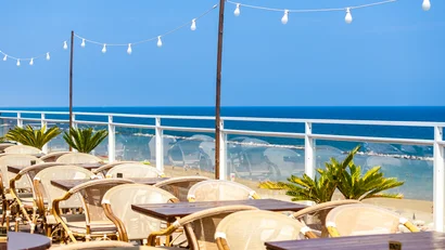 Tavoli all'aperto con vista sul mare e luci decorative al tramonto