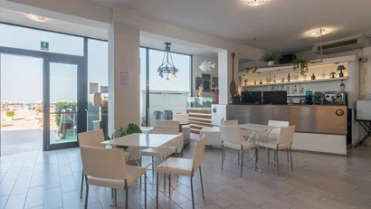 Interno di un bar con tavoli bianchi e vista sulla spiaggia