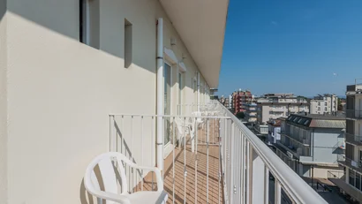 Balcone lungo con sedie bianche e vista sulla città in una giornata soleggiata