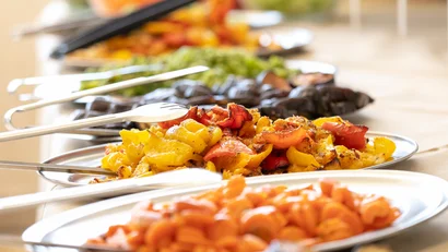Piatto di verdure grigliate arancioni, gialle e rosse su un buffet