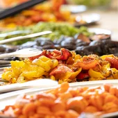 Piatto di verdure grigliate arancioni, gialle e rosse su un buffet