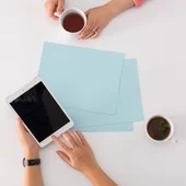 Due persone con tazze di tè e tablet su tavolo bianco