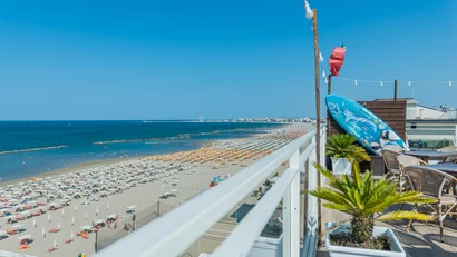 Vista dal balcone di una spiaggia affollata con ombrelloni colorati e mare blu
