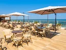 Terrazza ristorante con tavoli, sedie e ombrelloni vista mare.