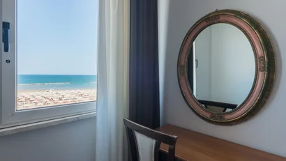 Vista sulla spiaggia dal tavolo con sedia e specchio ovale in stanza