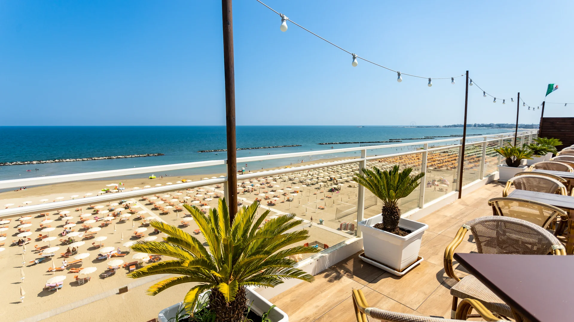 Vista dal balcone su una spiaggia con ombrelloni, mare e cielo sereno